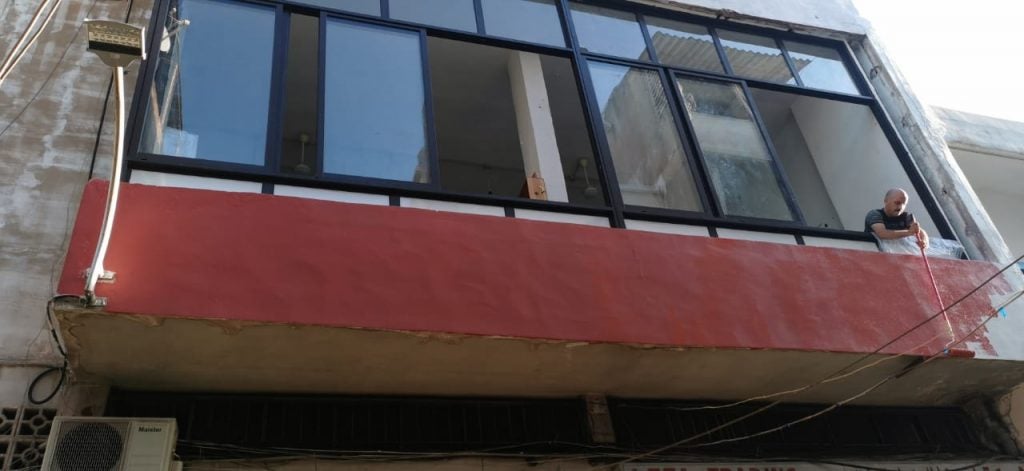 A man paints the outside of Traboulsi's studio with red paint.